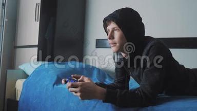 青少年和操纵杆男子网络运动帽衫吸收在线电子游戏。 少年生活方式少年在兜帽里